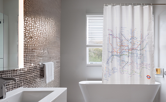 Underground map shower curtain hanging up in in bathroom with metallic tiles