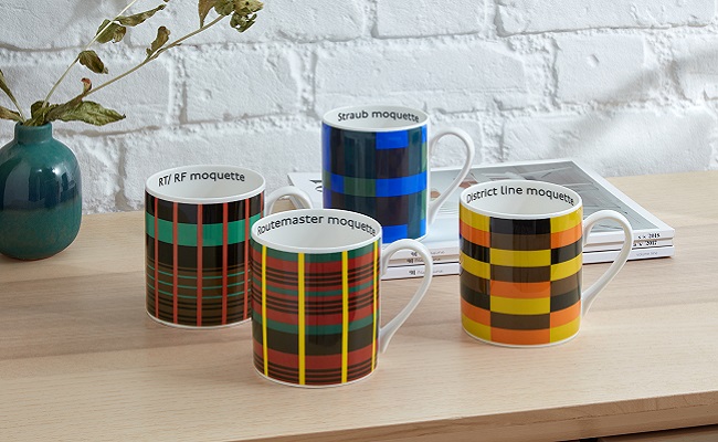 Four moquette print china mugs sitting on wooden table top