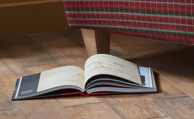 Open Hidden London book on wooden panel floor with Routemaster sofa behind