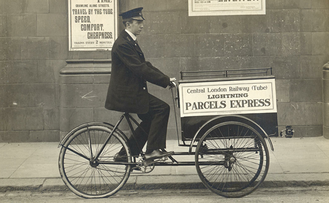 Man on bicycle peddling news cart in black and white