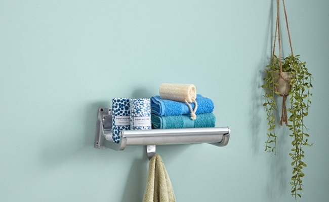 Silver luggage rack mounted on pale blue bathroom wall
